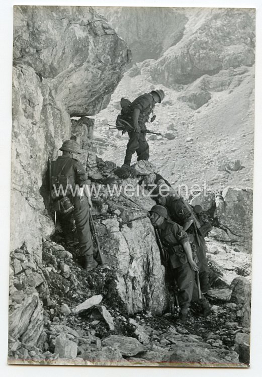 Wehrmacht Heer Pressefoto: Fest angedrückt an den Felsen sind die Männer geschützt vor Beschuss und Steinschlag